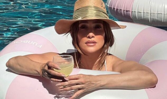 Jennifer Lopez posando en bikini blanco junto a una piscina en una lujosa villa de Los Ángeles para su Instagram.