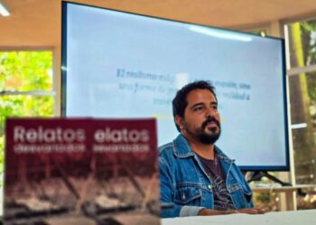 El escritor morelense Jorge Antonio Mora conversando con el público asistente y mostrando su libro dentro de la biblioteca pública del Parque Melchor Ocampo en Cuernavaca.